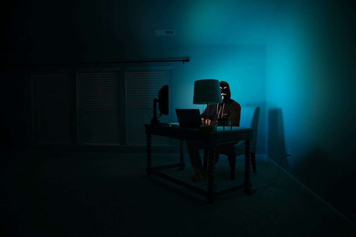 A person working at a computer in a dark room lit in blue