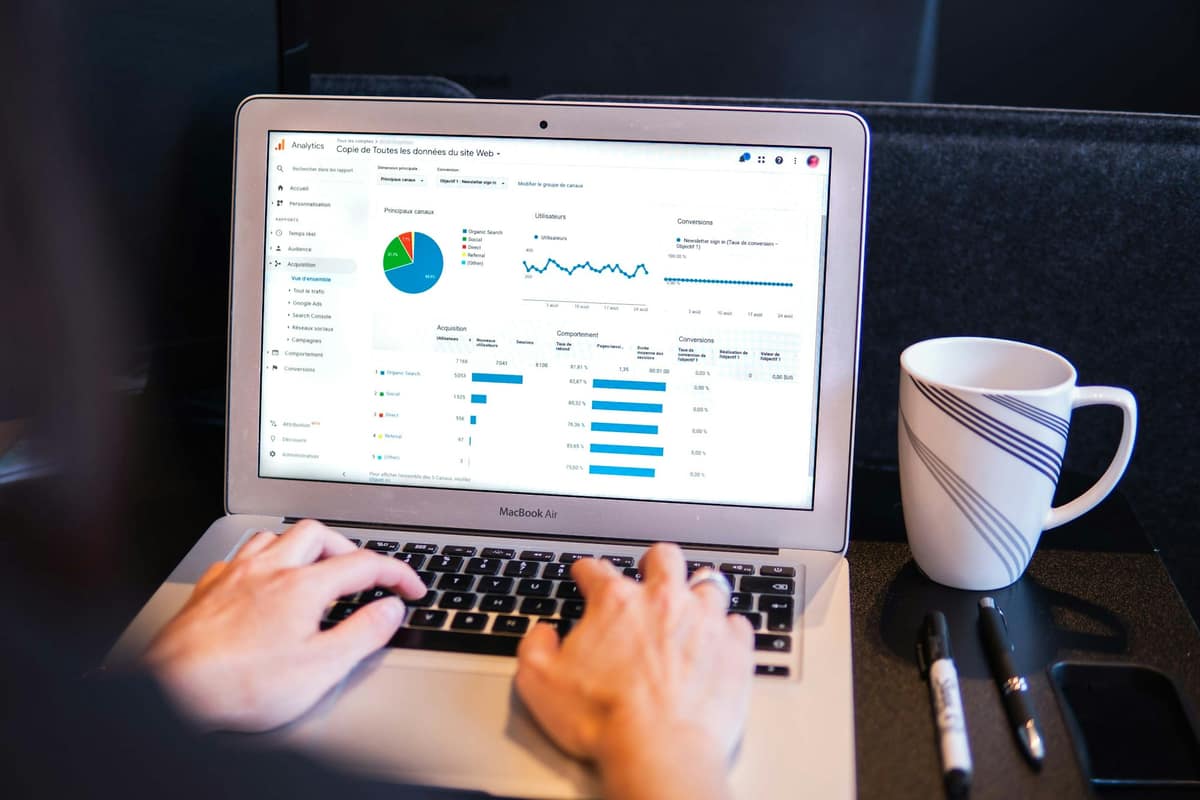 Laptop yang menampilkan dashboard bisnis di samping cangkir kopi