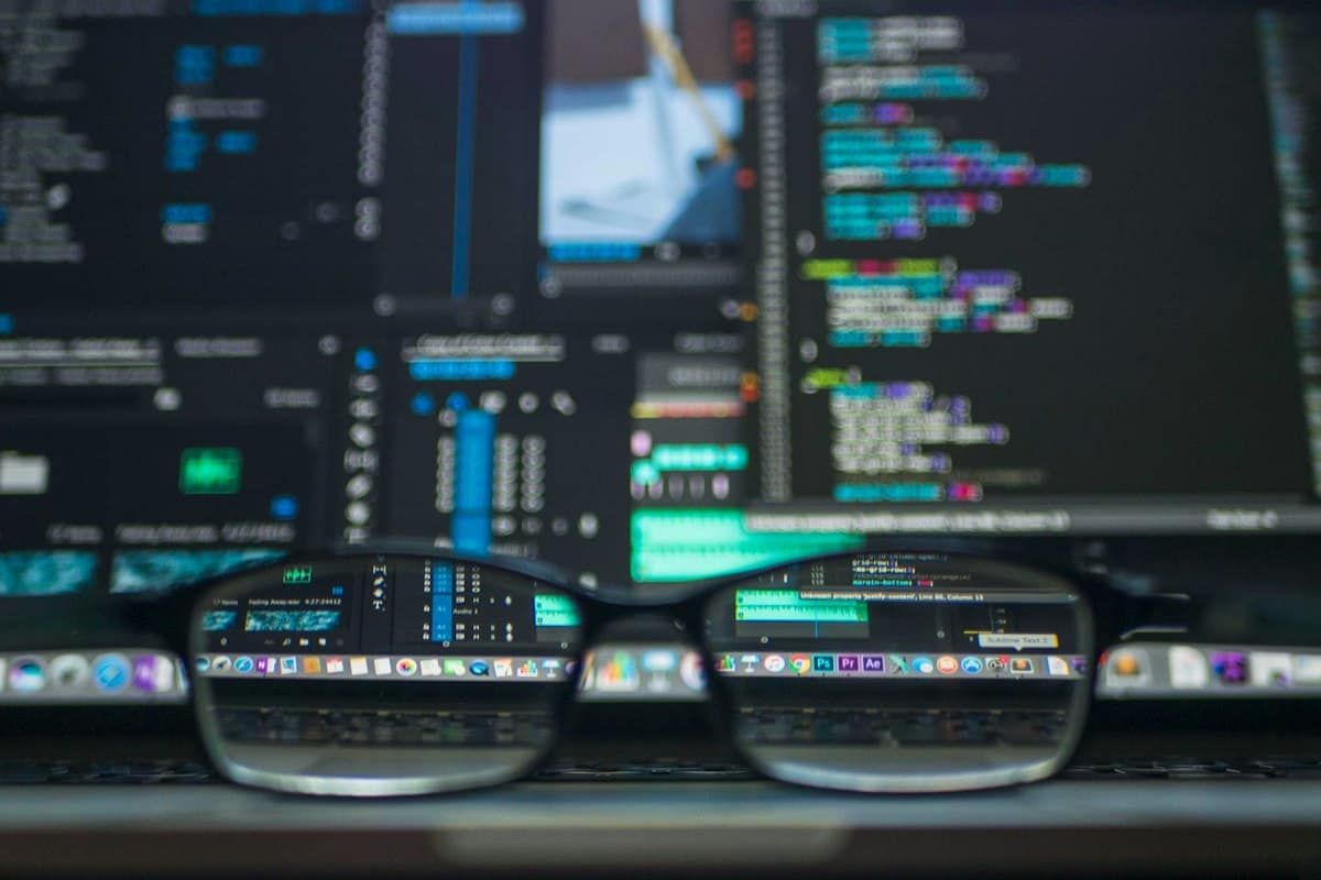 Kode di dua monitor terlihat melalui sebuah kacamata