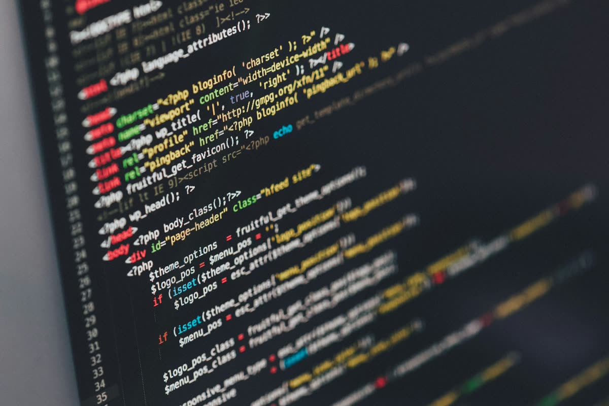 Kode PHP di layar editor berlatar gelap, difoto dari samping