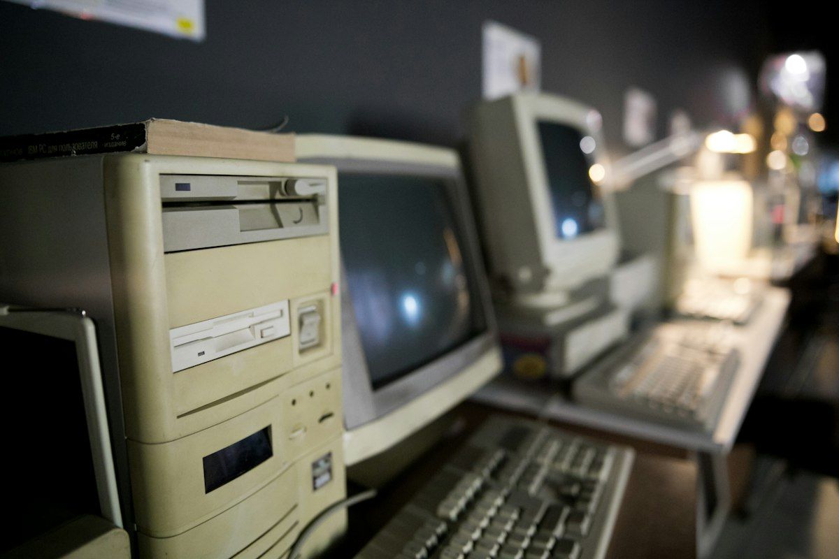 Row of old beige desktop computers with CRT monitors on an office desk