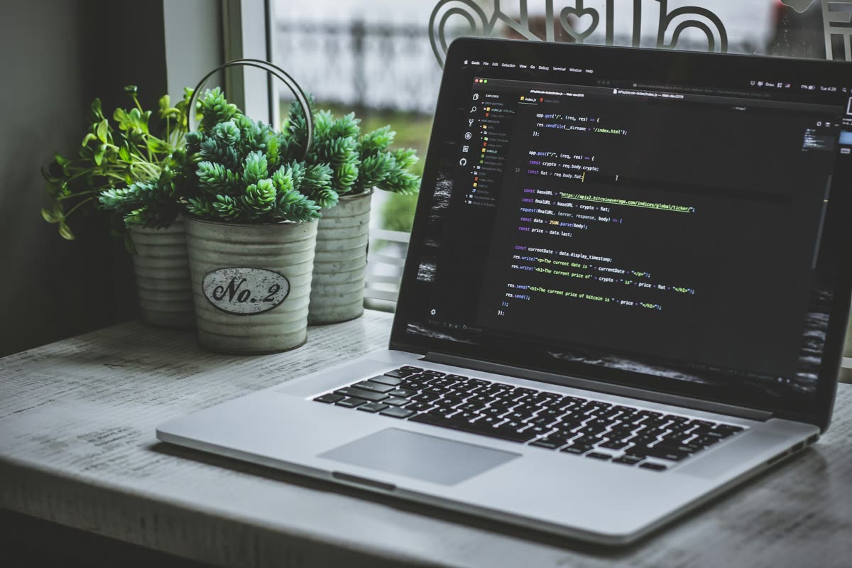 A laptop on a desk showing Node.js server code in a code editor