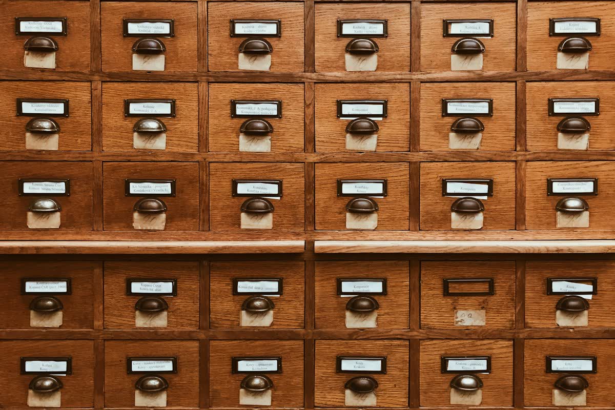 Deretan laci katalog perpustakaan dari kayu dengan pegangan logam dan label kertas