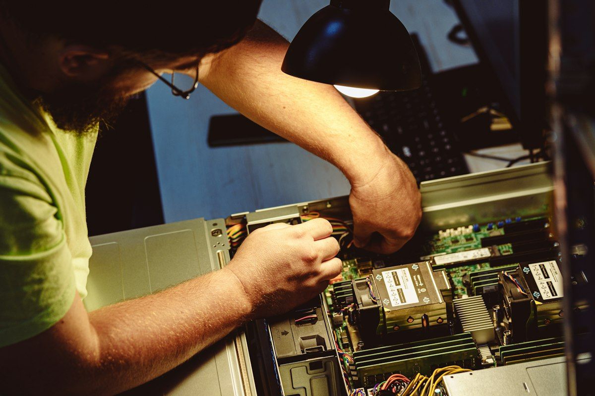 Technician working inside an open server under a desk lamp