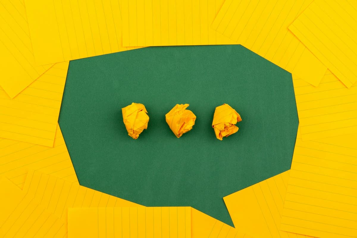 A green speech bubble cut from paper on a yellow background